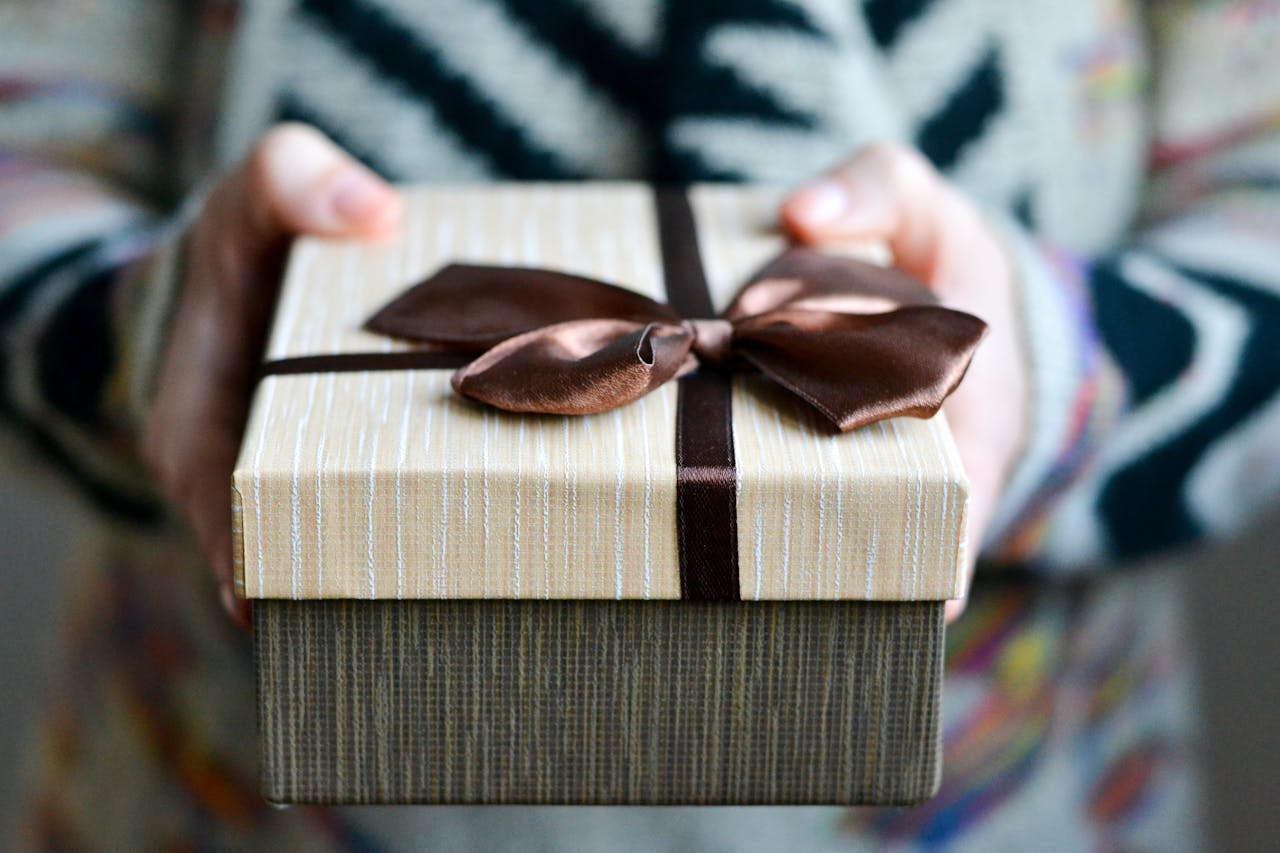 Stylish gift box with brown ribbon held in hands, perfect for holidays and celebrations.